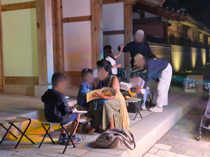 자전거 도서관 옆 캠핑 의자에서 외국인 관광객과 시민들이 책을 읽으며 휴식을 즐기고 있다.