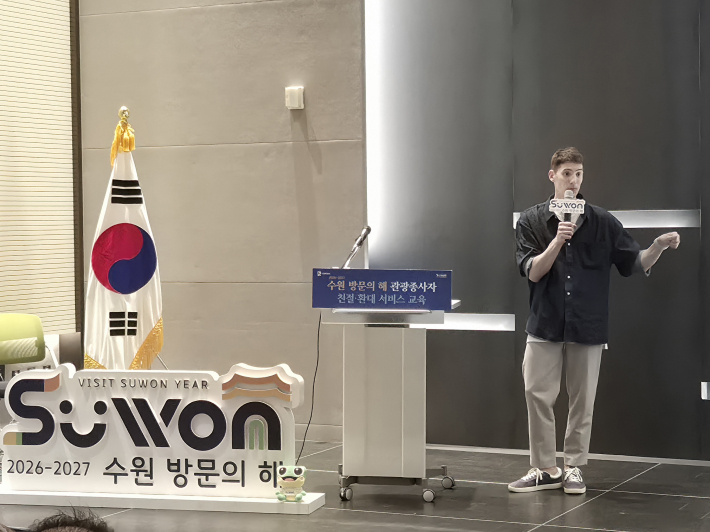 파비앙이 수원방문의해 로고 앞에서 한국 관광의 매력과 발전 방향에 대해 이야기하고 있다.