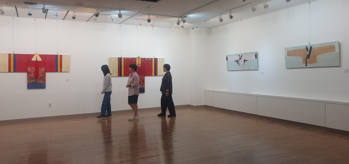 관람객들이 강남철 작가의 붉은 활옷 형상 작품을 살펴보고 있다. 작가는 전통 활옷에 개인의 기억과 감정을 담았다.