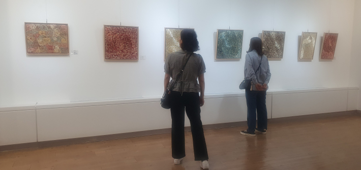관람객들이 이수진 작가의 보리줄기 작품을 감상하고 있다. 천연염색한 보리줄기가 반복되며 화면에 독특한 질감을 만든다.