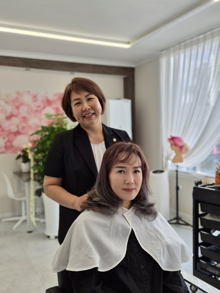 머리손질을 마친 고객과 함께 기념사진을 찍으며 환하게 웃고 있는 최지영 명장
