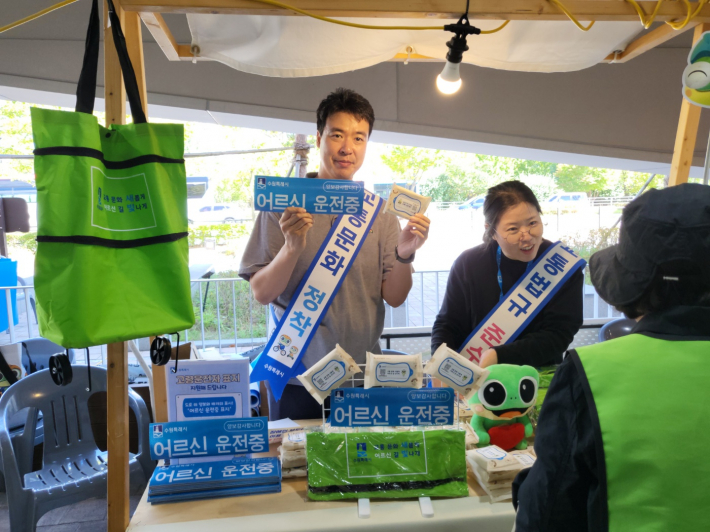 어르신들의 야간 보행 안전을 위해 형광색 교통안전 장바구니를 배부하고 있는 교통안전 홍보부스