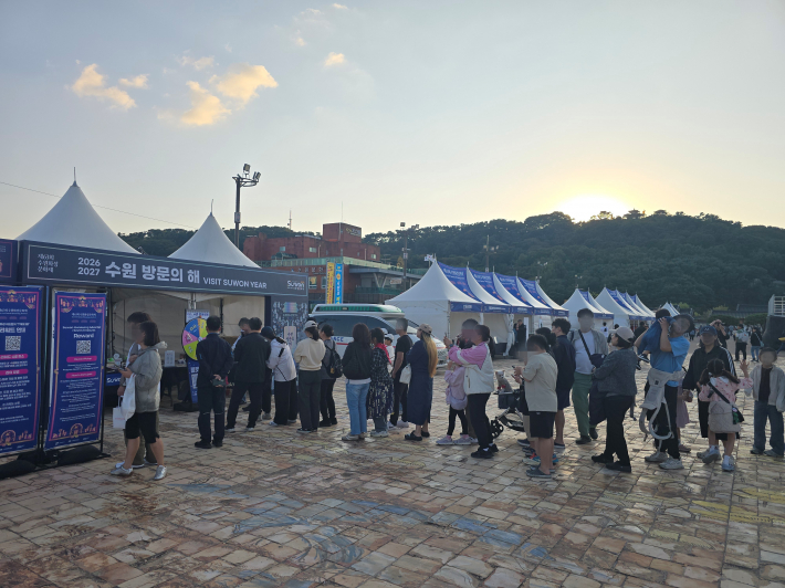 제63회 수원화성문화제 행사장에 마련된 '2026~2027 수원 방문의 해' 홍보 부스 앞에 방문객들이 줄을 서 있다.