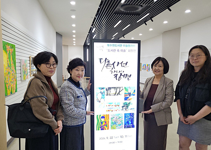 '도서관 속 미술' 회원전 홍보용 디지털 엑스배너 앞에서 작가들이 기념촬영을 하고 있다.
