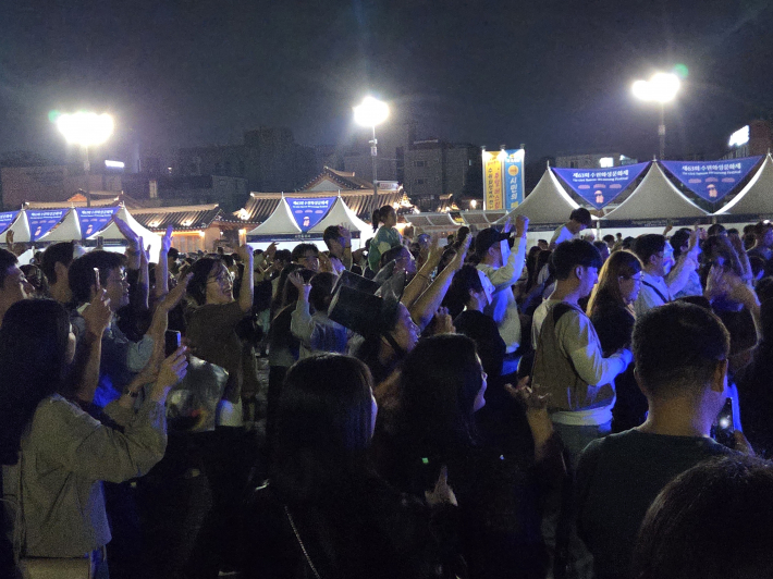 손을 높이 들어 흔들고, 리듬에 맞춰 몸을 움직이며 축제 즐겨    