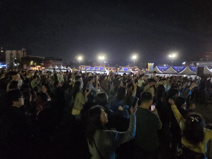 손을 높이 들어 흔들고, 리듬에 맞춰 몸을 움직이며 축제 즐겨    
