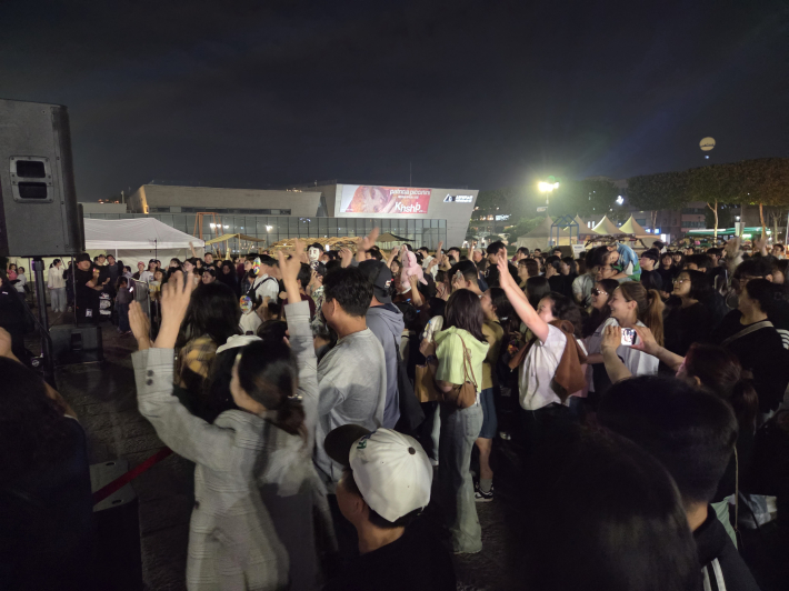 손을 높이 들어 흔들고, 리듬에 맞춰 몸을 움직이며 축제 즐겨    