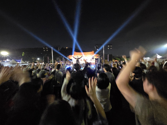 손을 높이 들어 흔들고, 리듬에 맞춰 몸을 움직이며 축제 즐겨    