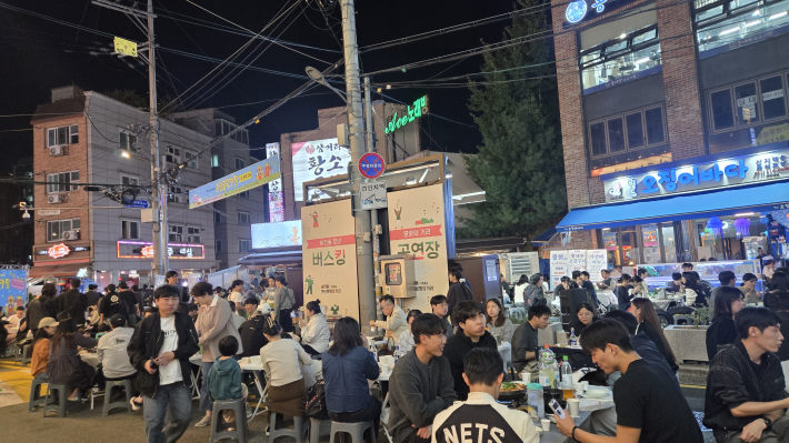 버스킹 존 주변으로 빽빽하게 들어선 야외 테이블에서 젊음의 에너지를 발산하며 축제의 밤을 만끽하고 있다