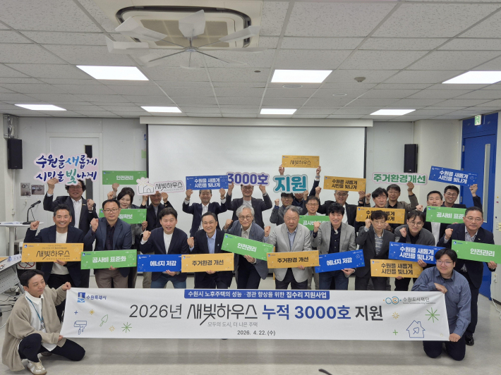사진3) 수원도시재단과 집수리 지원사업 관계자들이 새빛하우스 3천호 지원을 기념하는 손팻말을 들고 있다.    