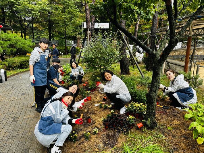 영통중학교 학생과 학부모, 교직원이 함께 꽃을 심으며 열린 정원을 조성하고 있다.     